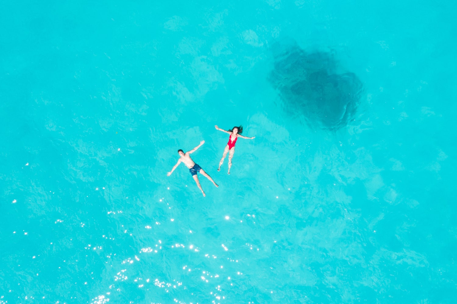 Aerial view with a drone on Honeymooners swimming in Bora Bora's lagoon, lost in the blue