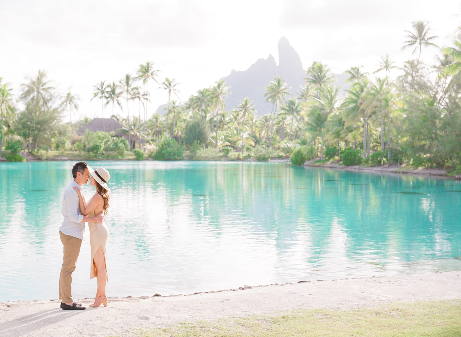 Couple kissing in the St. Regis Bora Bora at the lagoonarium spa with the palms and mount Otemanu
